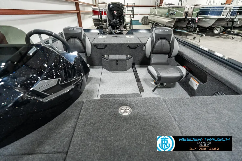 Slide: The Image of 2025 Lund 1875 Pro-V Bass XS interior with seating and steering wheel, showcased in a showroom. - 12