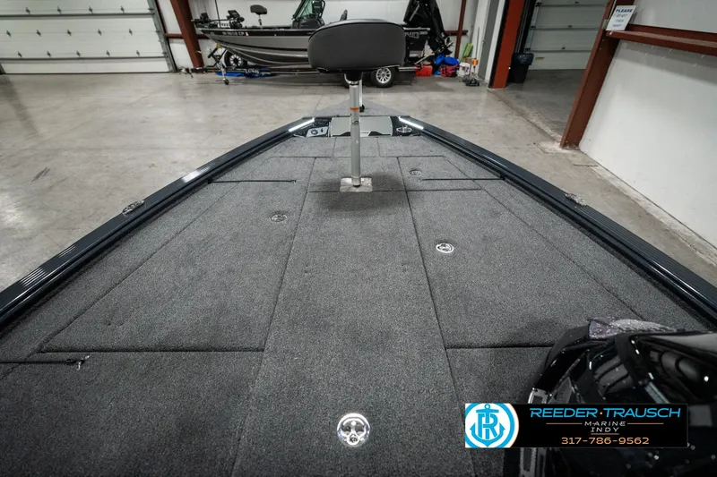 Slide: The Image of 2025 Lund 1875 Pro-V Bass XS boat interior with carpeted deck in showroom. - 18