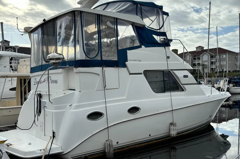 Slide: The Image of 1998 Silverton 352 Motor Yacht docked at marina under cloudy sky. - 1