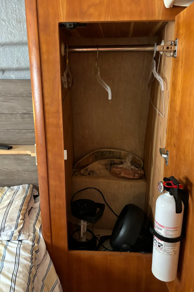 Slide: The Image of 1998 Silverton 352 Motor Yacht interior closet with hangers and fire extinguisher. - 47