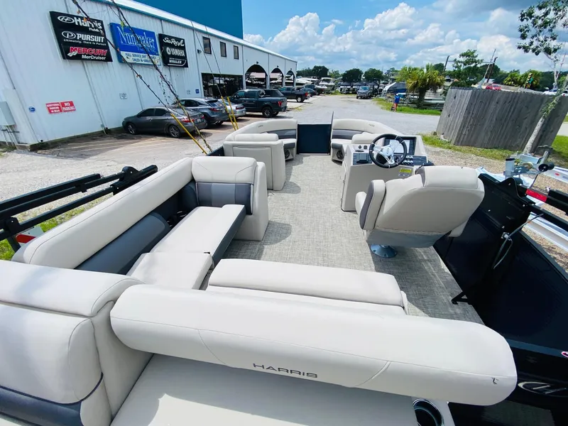 Slide: The Image of 2023 Harris Cruiser 230 pontoon boat with spacious seating, parked outside dealership. - 17