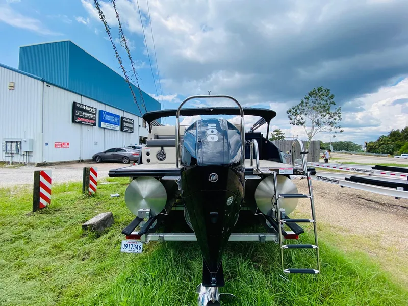 Slide: The Image of 2023 Harris Cruiser 230 pontoon boat with outboard motor, parked near industrial building. - 5