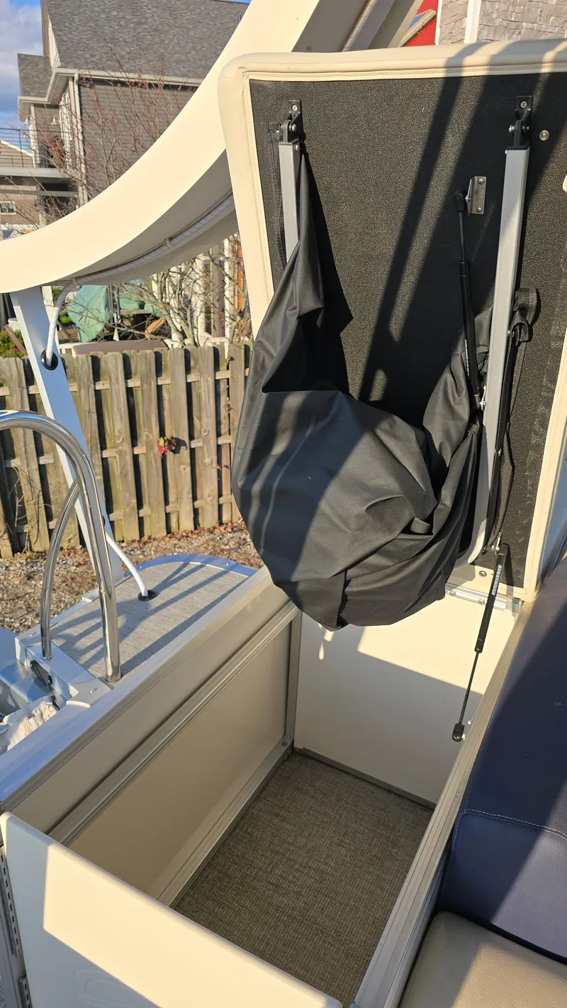 Slide: The Image of 2023 Avalon Catalina Cruise Funship storage compartment with open lid and black cover. - 13