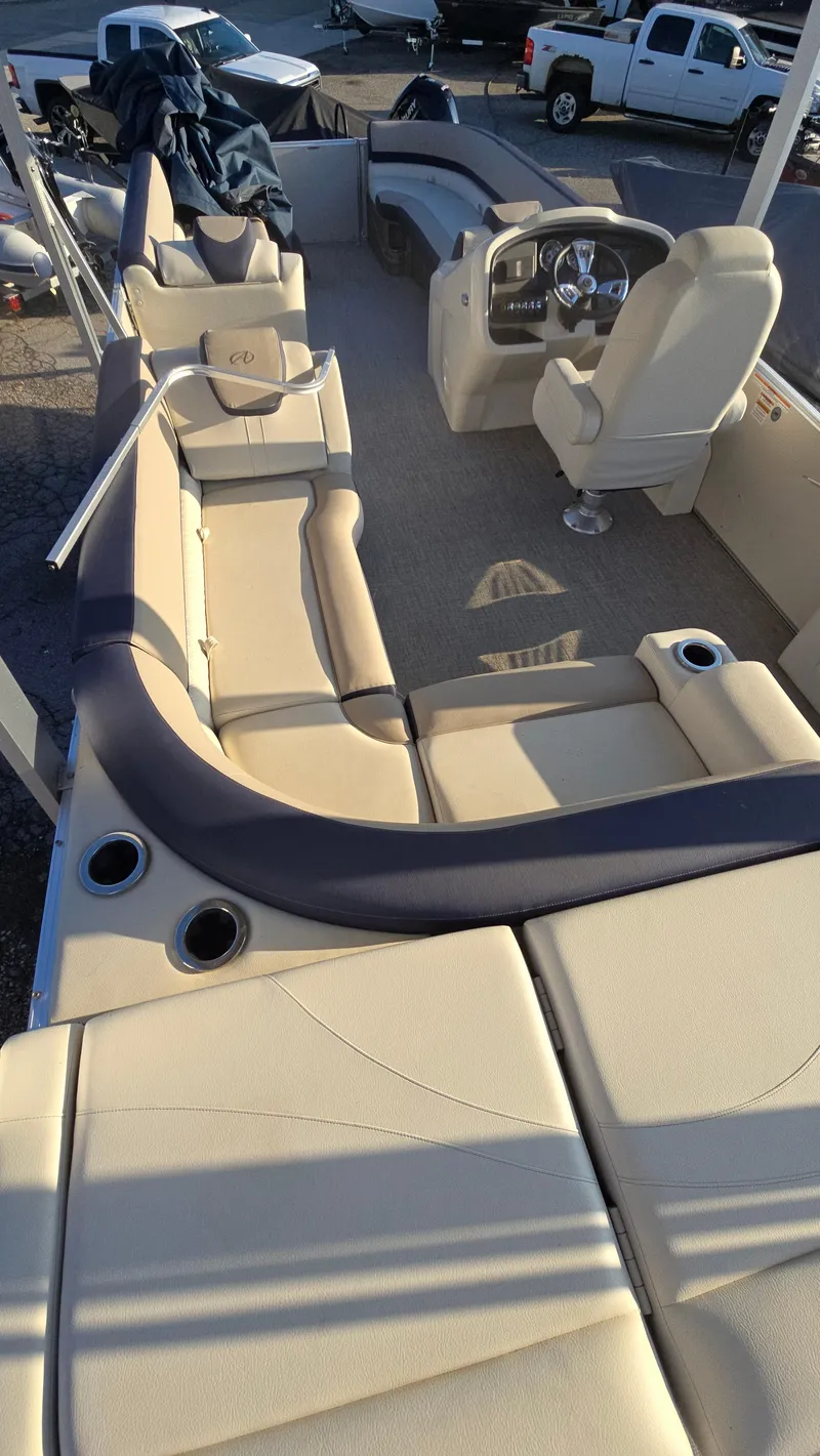 Slide: The Image of 2023 Avalon Catalina Cruise Funship boat interior with beige seating and steering console. - 2