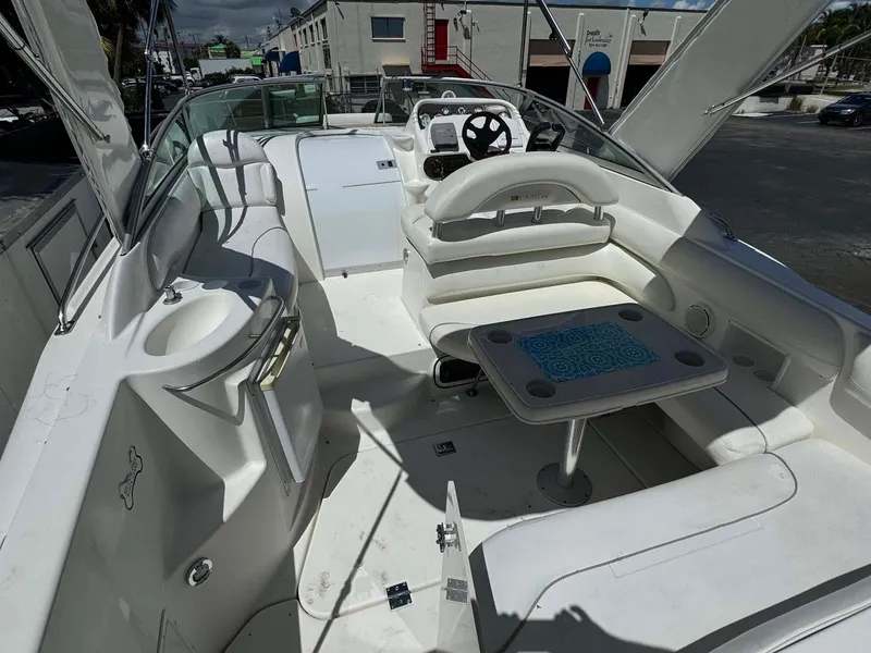 Slide: The Image of 2002 Larson 310 Cabrio boat interior with seating and table, featuring a sleek white design. - 12