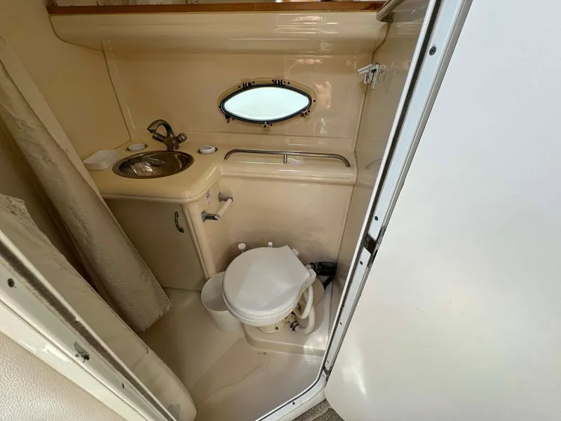 Slide: The Image of 2002 Larson 310 Cabrio boat bathroom with sink, toilet, and porthole window. - 31