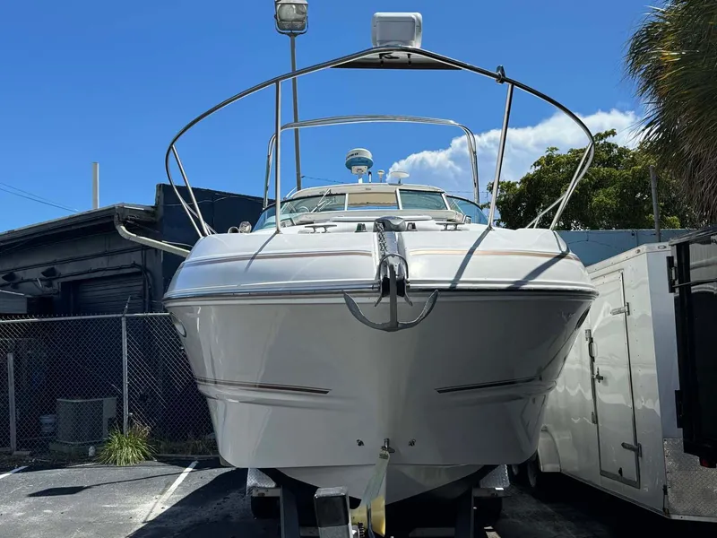 Slide: The Image of 2002 Larson 310 CABRIO boat on trailer, parked outdoors under clear blue sky. - 5