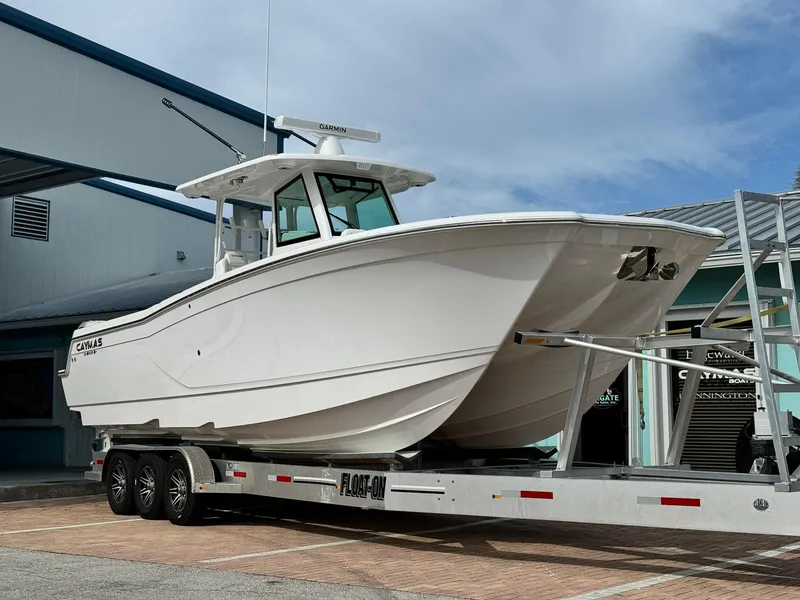 Slide: The Image of 2025 Caymas 30 CT boat on trailer, parked outdoors under cloudy sky. - 0