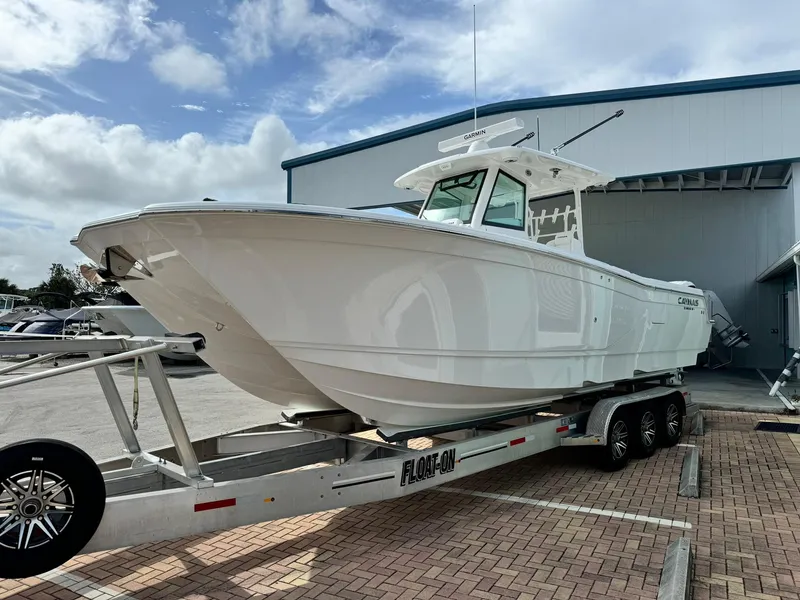 Slide: The Image of 2025 Caymas 30 CT boat on trailer, parked outdoors near a building. - 2