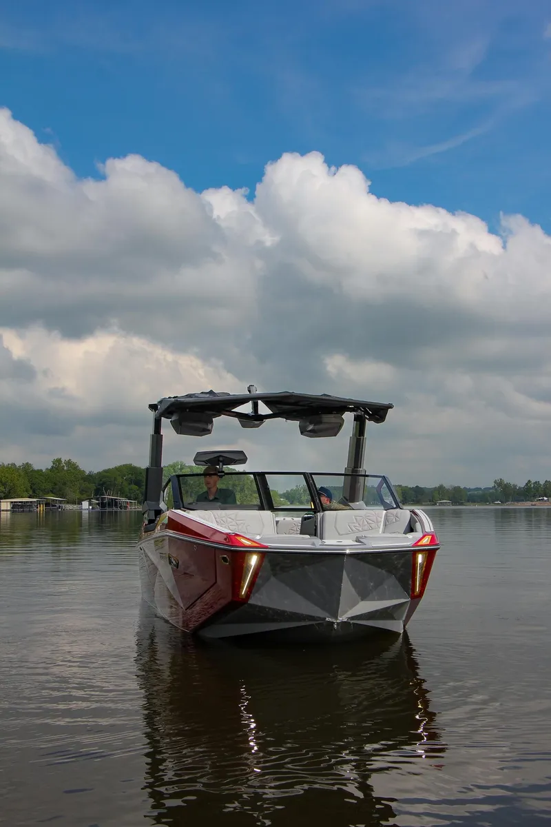 Slide: The Image of 2024 Nautique G23 Paragon boat on a calm lake under a cloudy sky. - 5