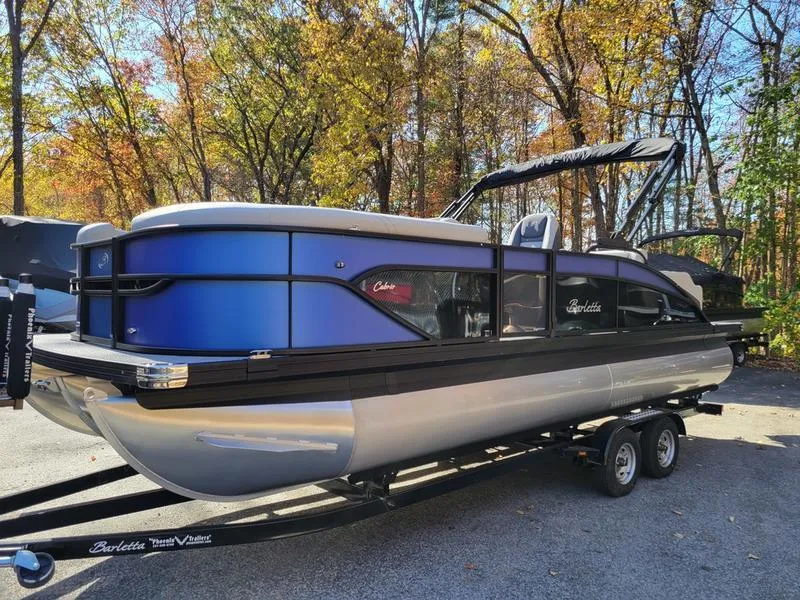 Slide: The Image of 2025 Barletta C22UC pontoon boat on trailer, parked in a wooded area. - 11
