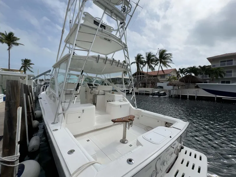 Slide: The Image of 2007 Cabo 35 Express boat docked in marina, featuring spacious deck and tower. - 0