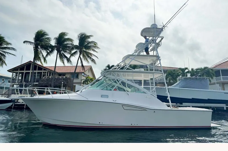 Slide: The Image of 2007 Cabo 35 Express yacht docked near palm trees and waterfront homes. - 1