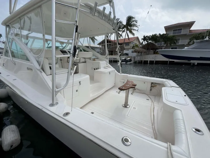 Slide: The Image of 2007 Cabo 35 Express boat docked in marina, featuring spacious deck and seating area. - 13