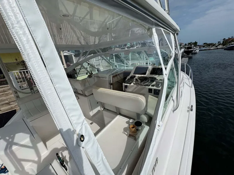 Slide: The Image of 2007 Cabo 35 Express boat interior with helm and seating, docked by the water. - 30