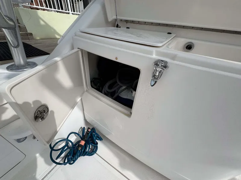 Slide: The Image of Open storage compartment on 2007 Cabo 35 Express boat with coiled blue hose. - 41