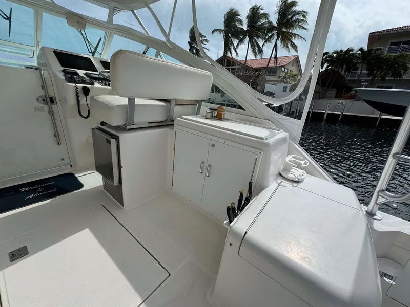Slide: The Image of 2007 Cabo 35 Express boat interior with helm, seating, and storage, docked near palm trees. - 44