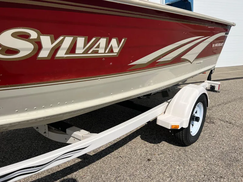 Slide: The Image of 1997 Sylvan 1600 Pro Select boat with red and beige design on a trailer. - 18