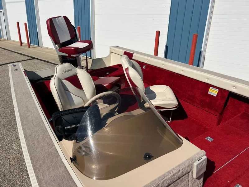 Slide: The Image of 1997 Sylvan 1600 Pro Select boat with red and white interior, parked near storage units. - 8