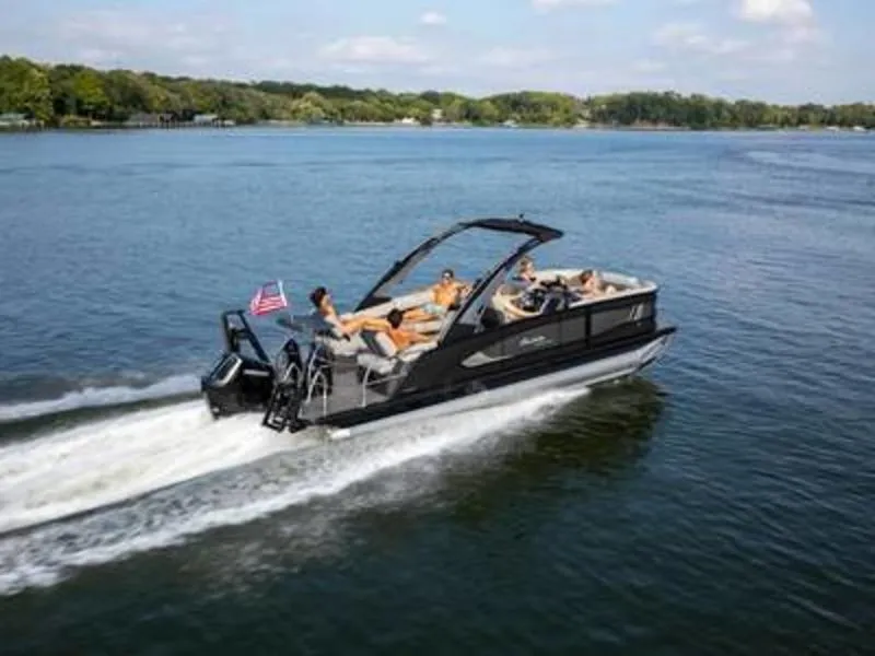 Slide: The Image of 2025 Barletta L23MA pontoon boat cruising on a lake with passengers enjoying the ride. - 2