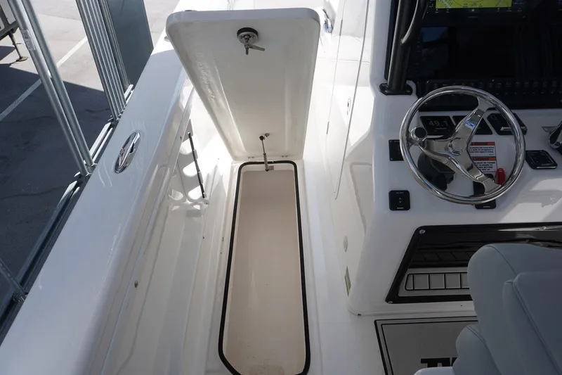 Slide: The Image of 2023 Twin Vee 280 GFX CC boat interior with open storage compartment and steering wheel. - 29