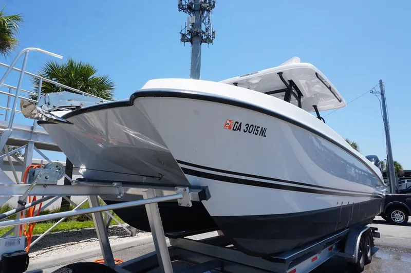 Slide: The Image of 2023 Twin Vee 280 GFX CC boat on trailer, sunny day, palm trees in background. - 3
