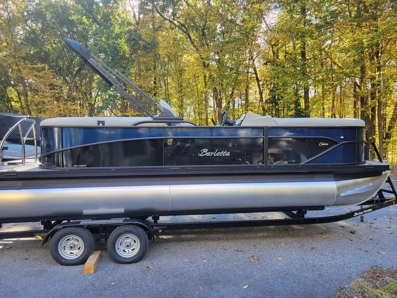 Slide: The Image of 2025 Barletta C22Q pontoon boat on trailer, surrounded by autumn trees. - 5