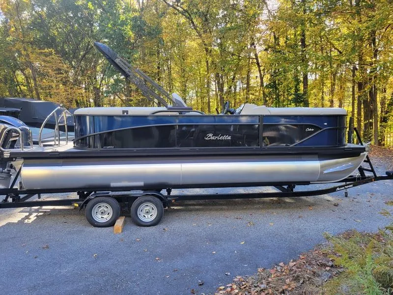 Slide: The Image of 2025 Barletta C22Q pontoon boat on trailer, surrounded by autumn trees. - 6