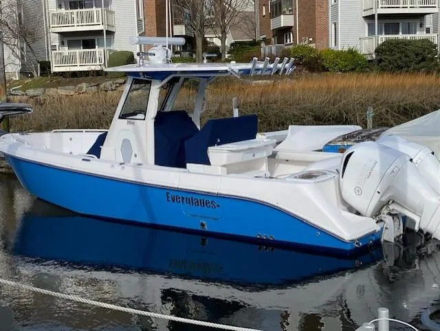 Slide: The Image of 2015 Everglades 295 Center Console boat docked in marina, blue and white design. - 4