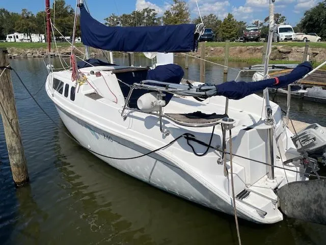The Image of 1998 Hunter 240 sailboat docked in a marina, featuring blue covers and calm waters. - 0