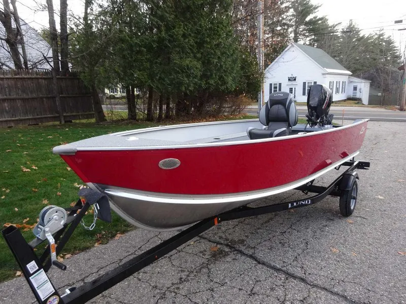 Slide: The Image of 2025 Lund 1600 Fury Heritage Edition boat on trailer, red exterior, parked outdoors. - 2