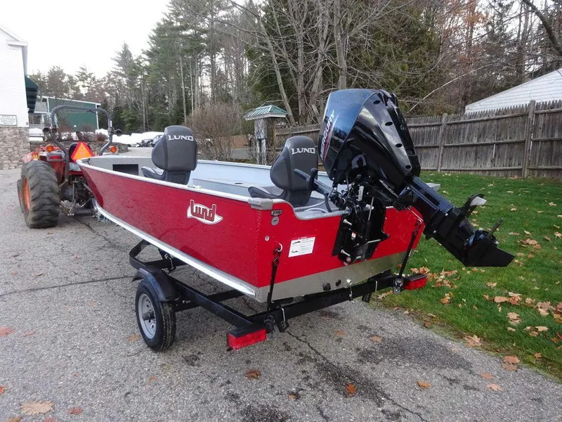 Slide: The Image of 2025 Lund 1600 Fury Heritage Edition boat on trailer, red exterior, parked outdoors. - 3
