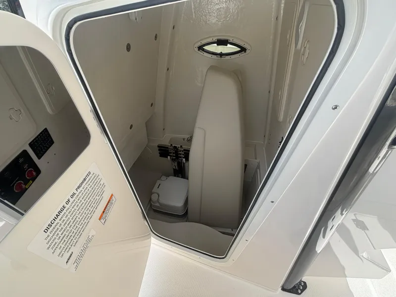 Slide: The Image of 2025 Sailfish 272 CC boat interior with compact marine toilet and storage space. - 15