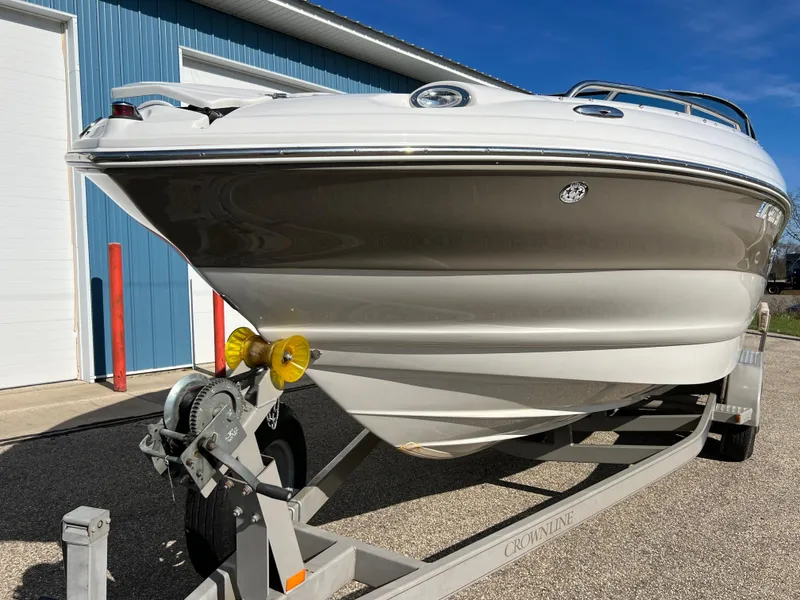 Slide: The Image of 2006 Crownline 260 LS boat on trailer, parked near blue building. - 14