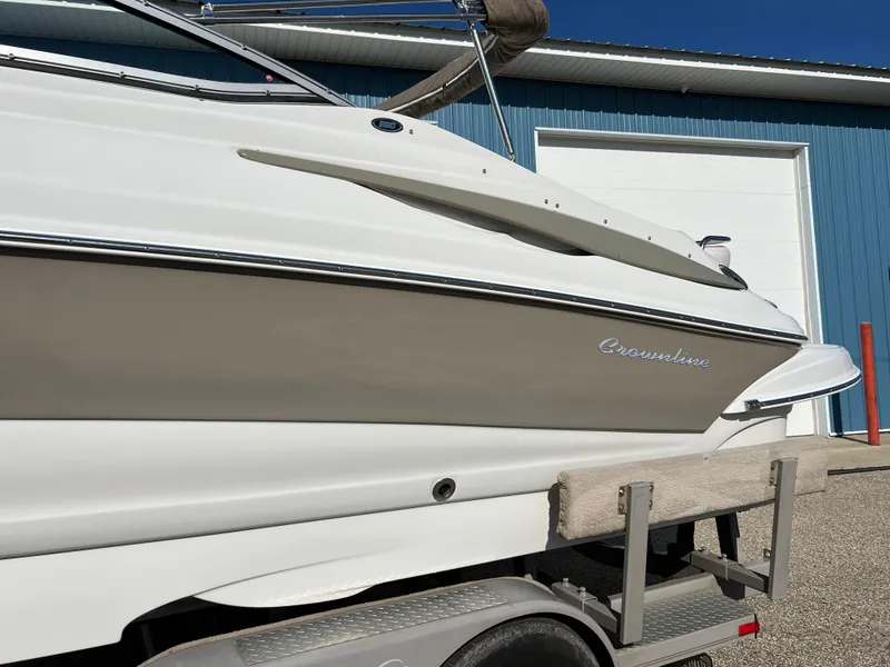 Slide: The Image of 2006 Crownline 260 LS boat on trailer, parked near blue building. - 18