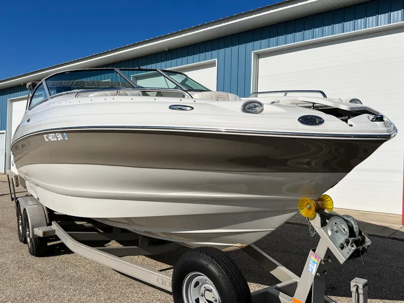 Slide: The Image of 2006 Crownline 260 LS boat on trailer, parked near blue building. - 24