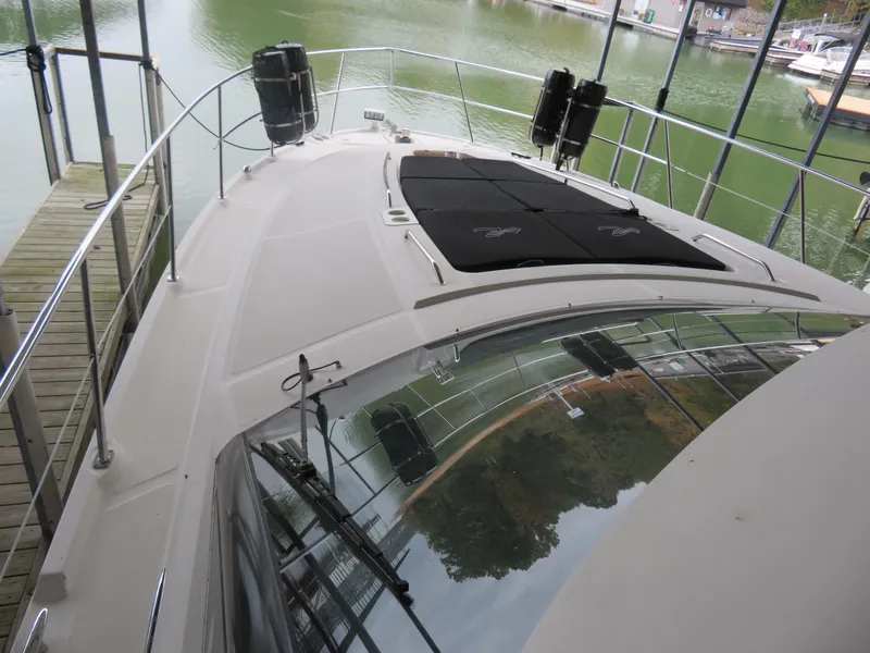 Slide: The Image of 2015 Sea Ray 470 Sundancer yacht docked, showcasing sleek deck design and spacious layout. - 13