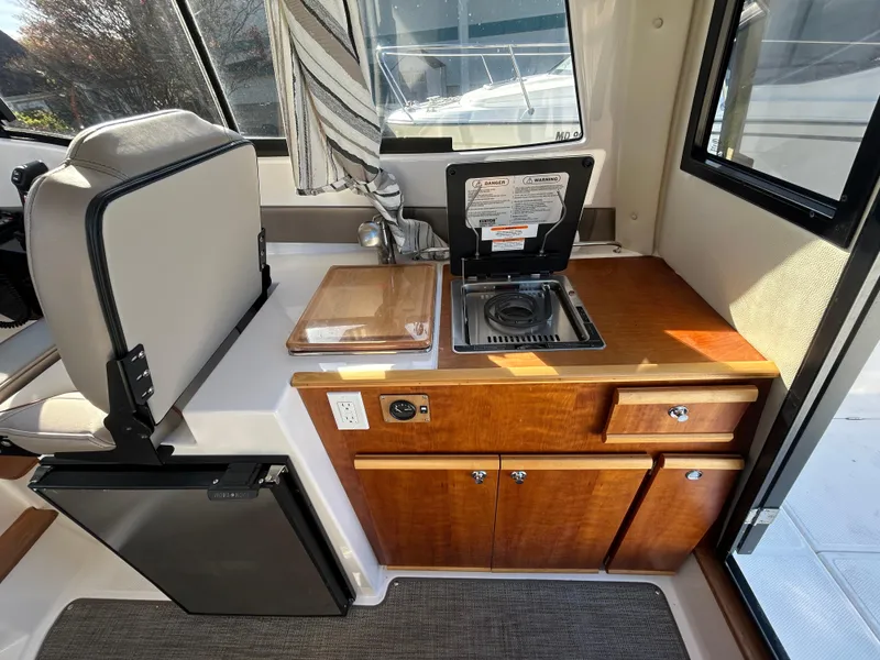 Slide: The Image of 2021 Cutwater C-24 Coupe interior kitchen with stove, sink, and compact fridge. - 8