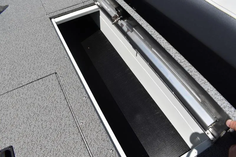 Slide: The Image of Open storage compartment on a 2025 Lowe SD224 boat, featuring a carpeted deck. - 24