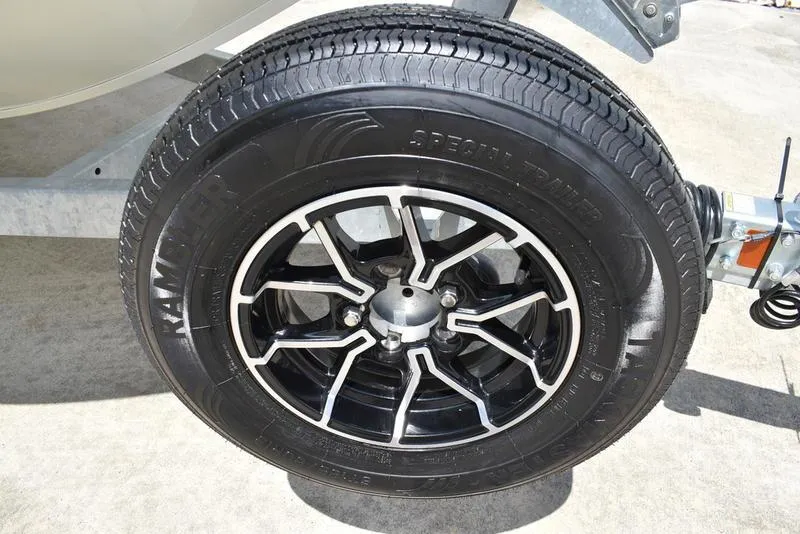 Slide: The Image of Close-up of a 2025 Lowe SD224 trailer tire with black alloy wheel on concrete. - 44