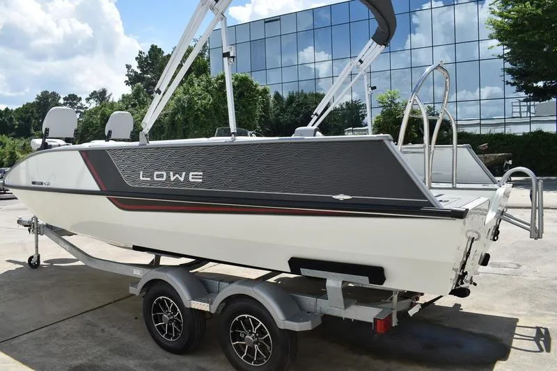 Slide: The Image of 2025 Lowe SD224 boat on trailer, parked outdoors near glass building. - 6