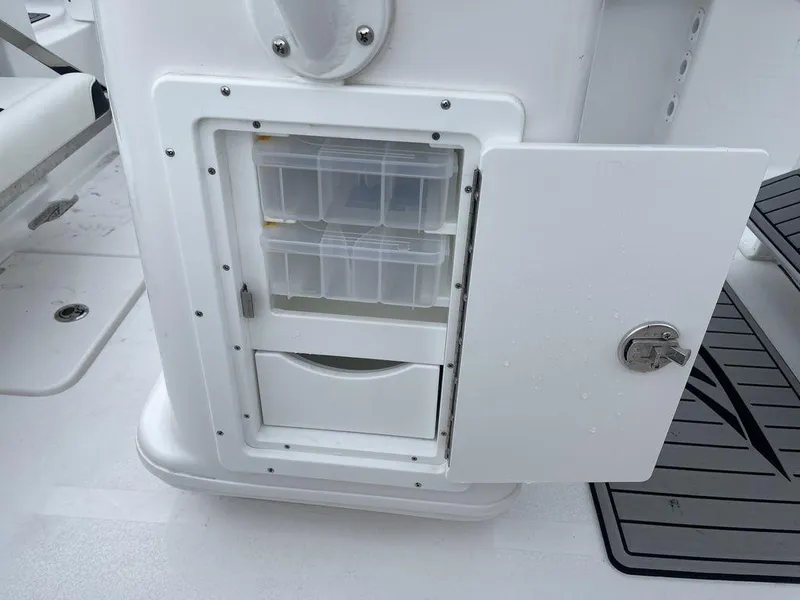 Slide: The Image of Tidewater 232cc 2025 boat storage compartment with open door and organized containers. - 12
