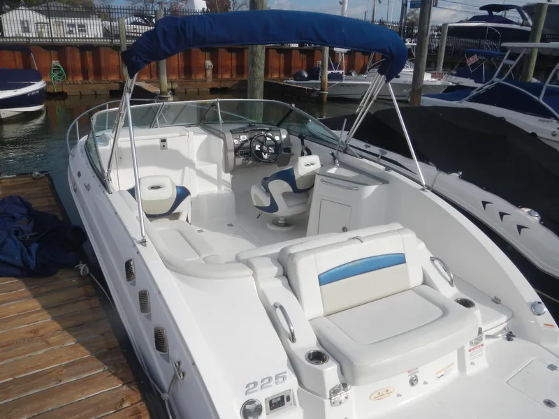 The Image of 2013 Chaparral 225 SSi boat with blue canopy docked at marina. - 0