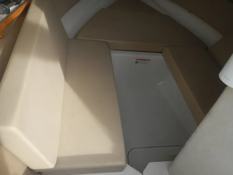 Slide: The Image of 2013 Chaparral 225 SSi boat interior with beige seating and storage area. - 9