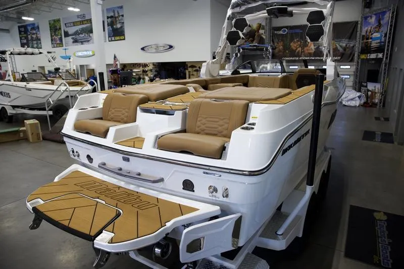 Slide: The Image of 2025 Malibu 26 LSV boat with tan seating in showroom. - 33