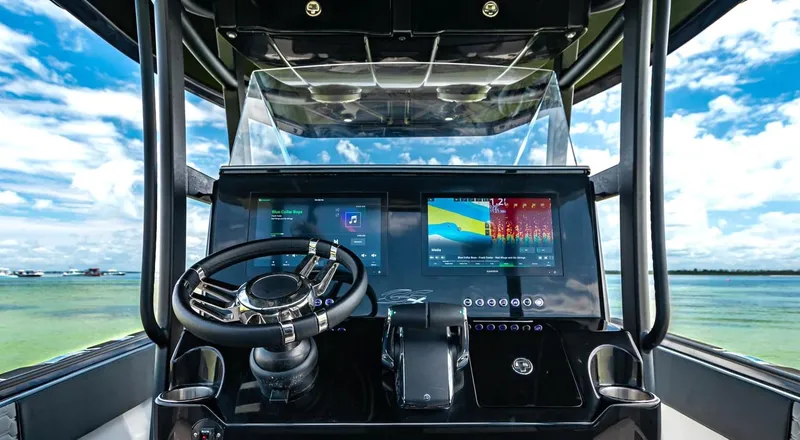 Slide: The Image of 2025 Glasstream GSX 360 LS boat dashboard with advanced navigation system, steering wheel, and scenic ocean view. - 4