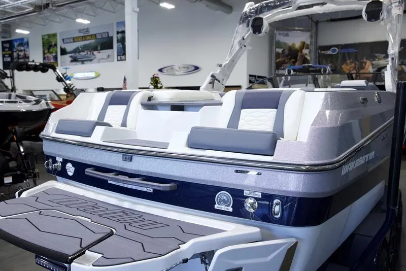 Slide: The Image of 2025 Malibu 24 MXZ boat interior, showcasing sleek seating and modern design in a showroom. - 10