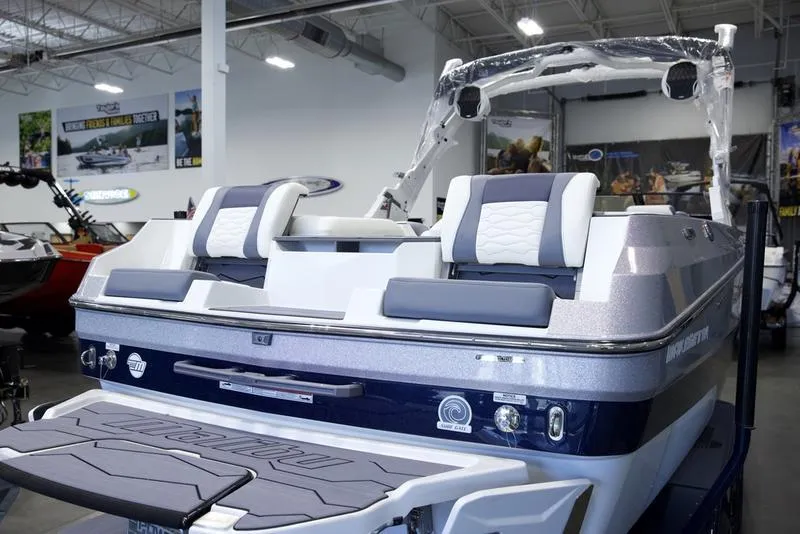 Slide: The Image of 2025 Malibu 24 MXZ boat interior with sleek seating in a showroom setting. - 11