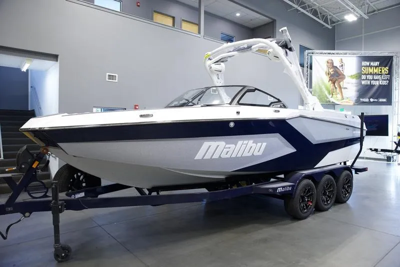 Slide: The Image of 2025 Malibu 24 MXZ boat in showroom, sleek design, on trailer. - 3