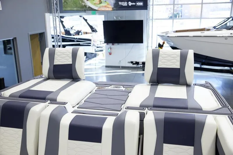 Slide: The Image of 2025 Malibu 24 MXZ boat interior with stylish seating in showroom. - 30